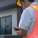 Building Inspector w/ clipbiard working in front building.